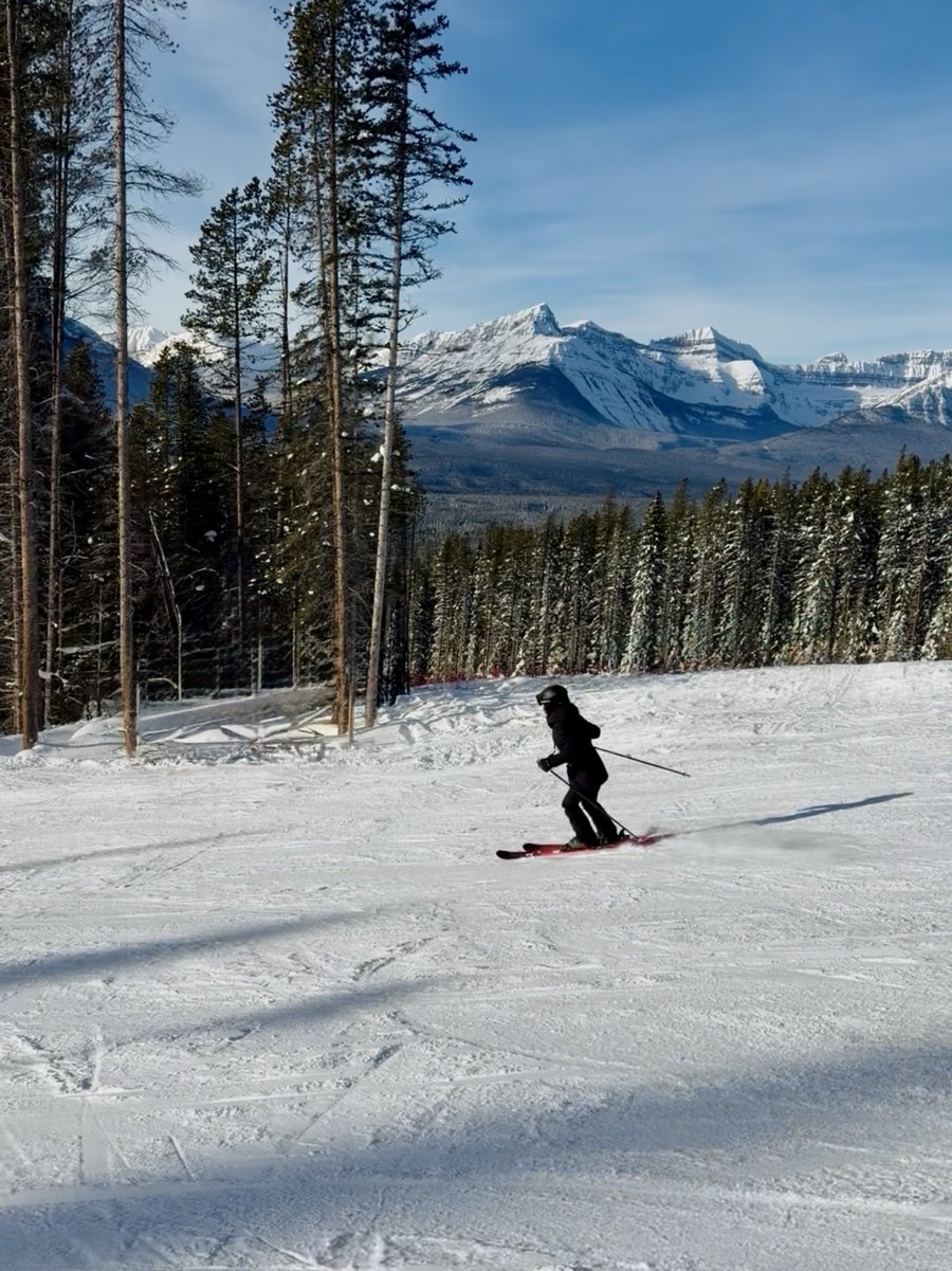 Eva skiing a groomed run below snowy Rocky Mountain peaks