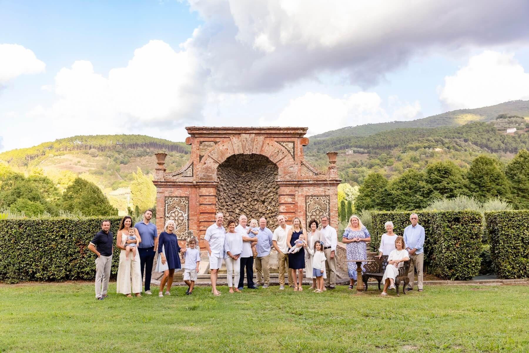 Three generations of an extended family gathered before a brick garden grotto at a Tuscan villa