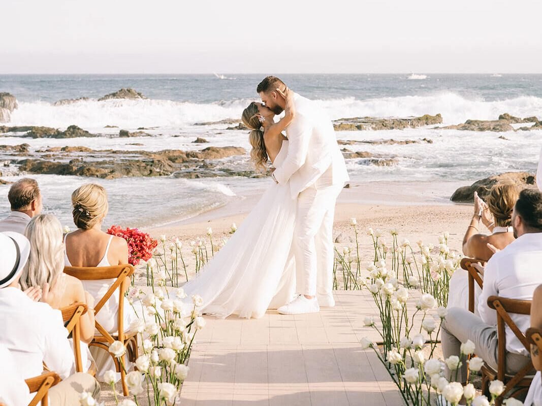 A couple kissing at a beachfront wedding ceremony