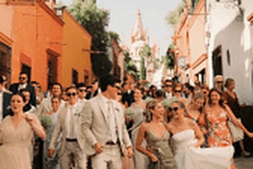 Wedding guests parading through a cobbled colonial street